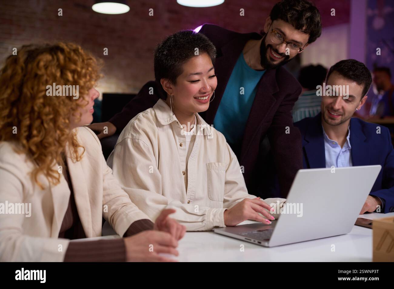 Collègues coopérant sur le projet en utilisant un ordinateur portable dans le bureau moderne la nuit Banque D'Images