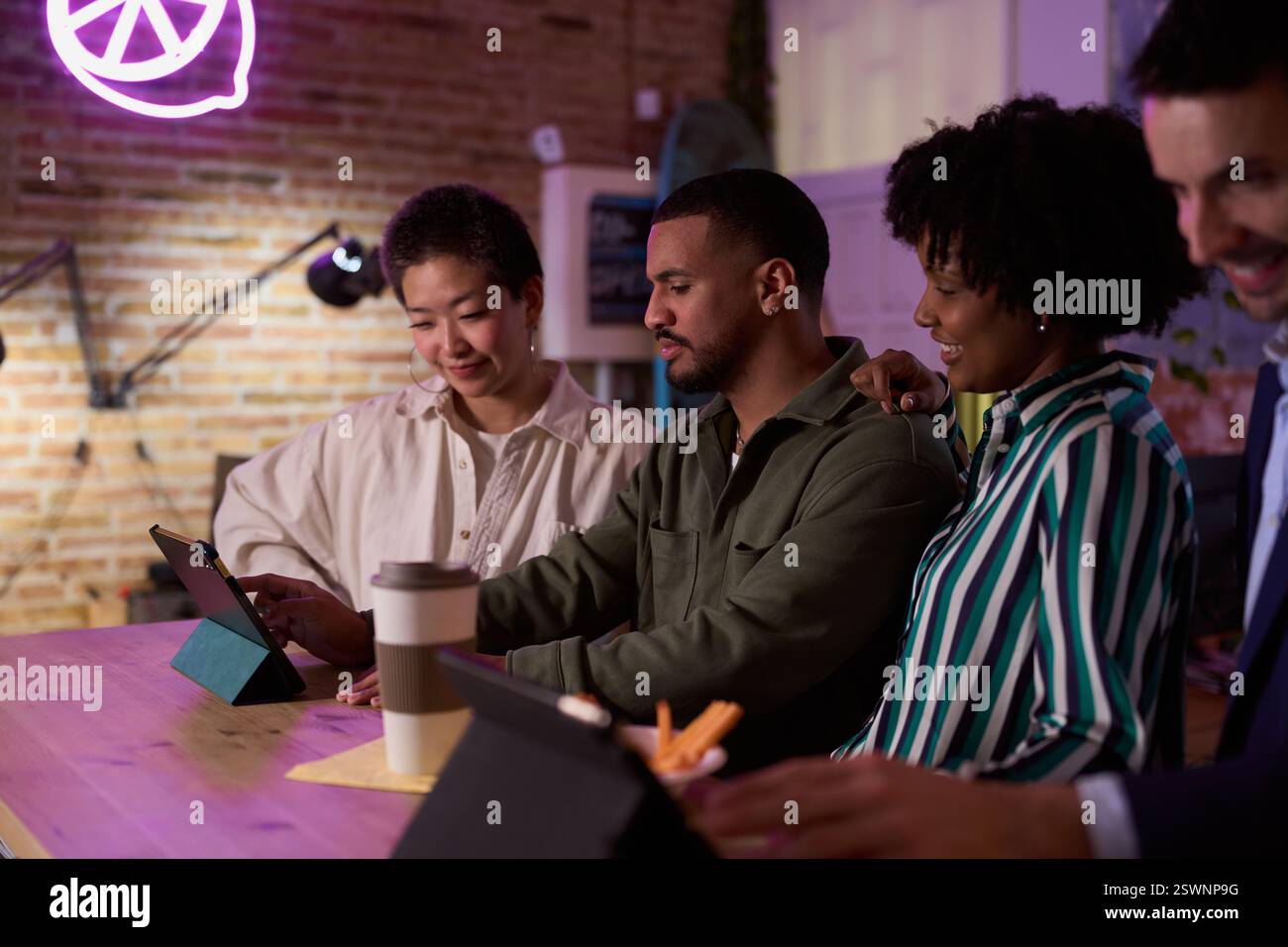 Équipe de démarrage diversifiée utilisant une tablette dans un bureau moderne après le travail Banque D'Images
