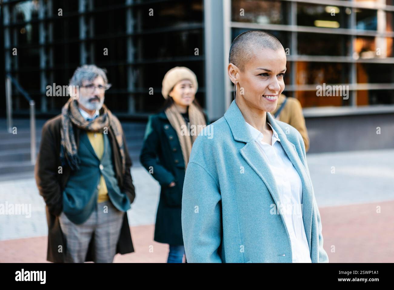 Femme d'affaires adulte moyenne réussie debout avec des collègues d'affaires à l'extérieur. Banque D'Images Femme d'affaires adulte moyenne réussie debout avec des collègues d'affaires à l'extérieur. Banque D'Images
