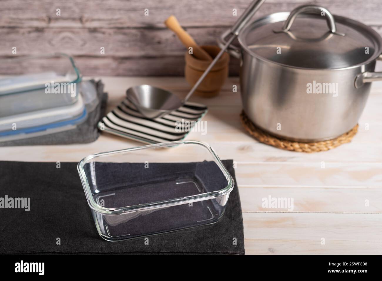 Récipient alimentaire en verre à côté d'un pot, d'une louche et d'un autre récipient alimentaire. Banque D'Images