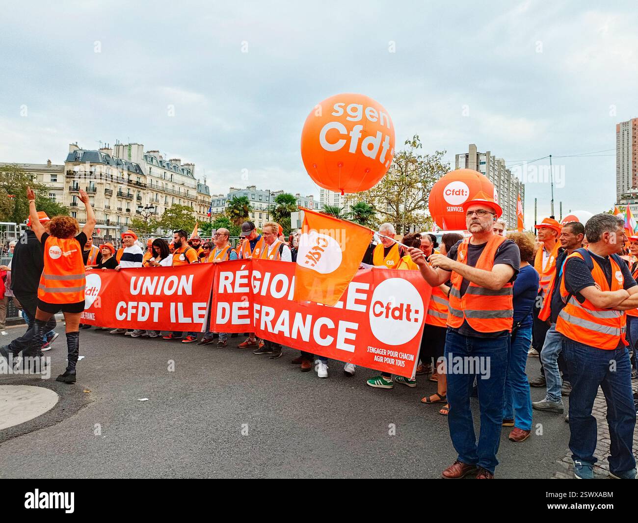 France, Paris, 2023-10-13. Manifestants syndicaux de la CFDT dans la rue avec des pancartes, des banderoles et des drapeaux habillés de gilets orange Banque D'Images