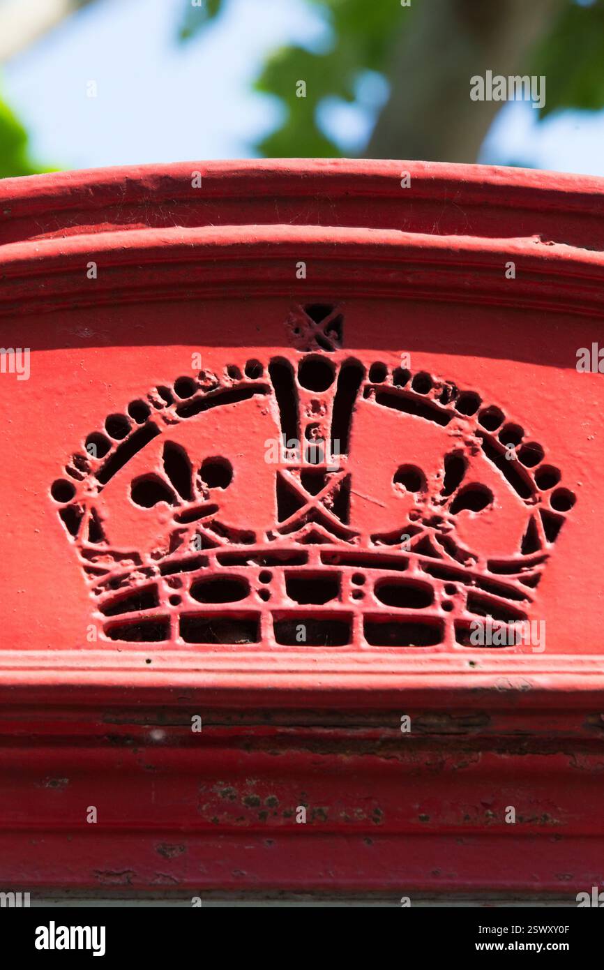 Gros plan d'une boîte aux lettres rouge, probablement au Royaume-Uni, avec un motif de couronne. L'emplacement n'est pas définitivement identifiable à partir de l'image seule. Banque D'Images