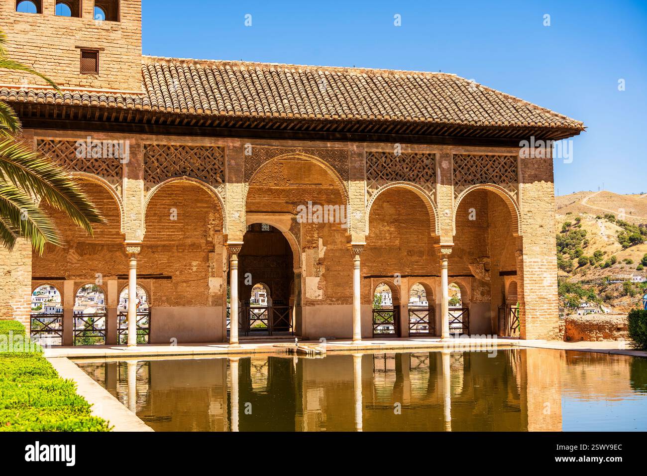 Le Palais Partal de l'Alhambra présente les Arches mauresques, la piscine réfléchissante et le paysage pittoresque de Grenade sous un ciel andalou clair Banque D'Images
