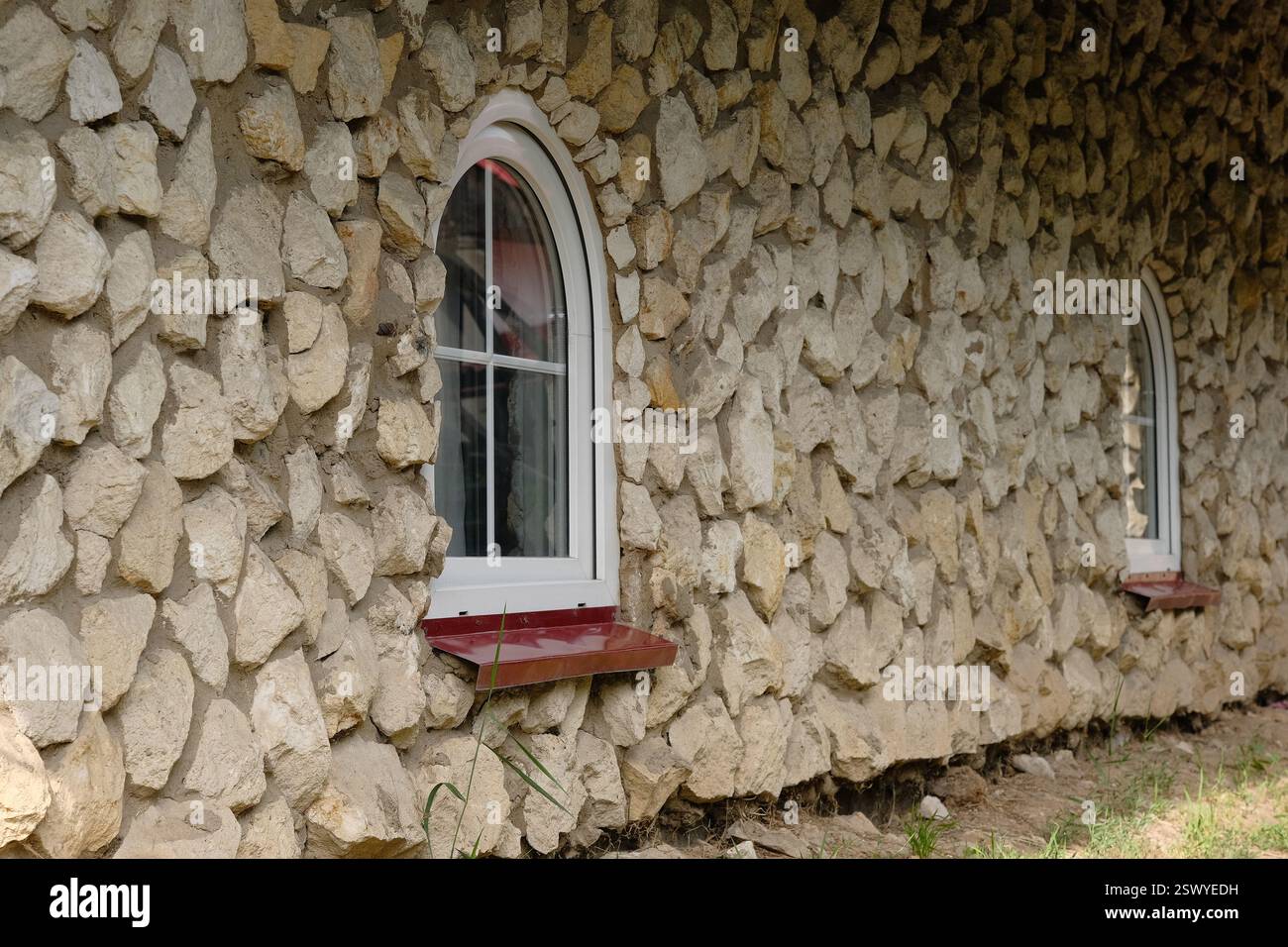Le mur de pierre avec deux fenêtres cintrées dans le style antique. Banque D'Images