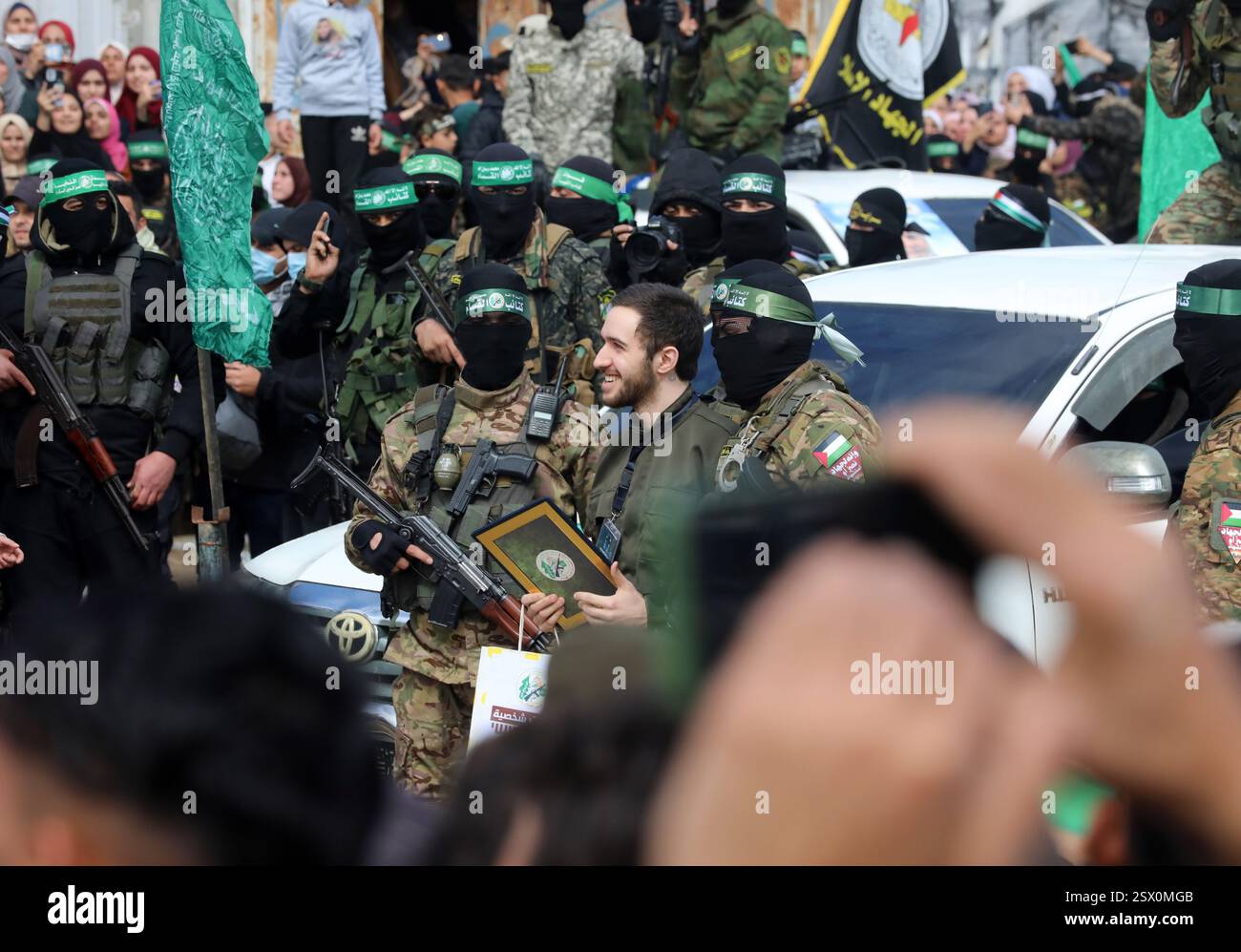 Gaza. 22 février 2025. Des membres des Brigades Al-Qassam, la branche armée du Hamas, et un otage israélien sont vus lors de la remise de trois otages israéliens au Comité international de la Croix-Rouge, dans le camp de réfugiés d’al-Nuseirat, dans le centre de Gaza, le 22 février 2025. Six otages israéliens précédemment détenus par le Hamas ont été libérés samedi dans le cadre d’un échange de cessez-le-feu en cours, ont confirmé les Forces de défense israéliennes (FDI) dans un communiqué. Crédit : Rizek Abdeljawad/Xinhua/Alamy Live News Banque D'Images Gaza. 22 février 2025. Des membres des Brigades Al-Qassam, la branche armée du Hamas, et un otage israélien sont vus lors de la remise de trois otages israéliens au Comité international de la Croix-Rouge, dans le camp de réfugiés d’al-Nuseirat, dans le centre de Gaza, le 22 février 2025. Six otages israéliens précédemment détenus par le Hamas ont été libérés samedi dans le cadre d’un échange de cessez-le-feu en cours, ont confirmé les Forces de défense israéliennes (FDI) dans un communiqué. Crédit : Rizek Abdeljawad/Xinhua/Alamy Live News Banque D'Images