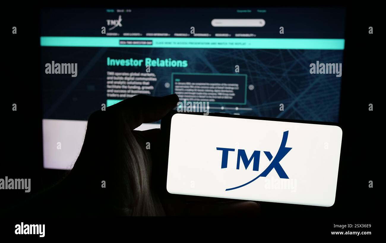 Dans cette illustration photo, une personne tient un téléphone mobile avec le logo de la société boursière canadienne Groupe TMX limitée sur l'écran devant la page Web. Banque D'Images