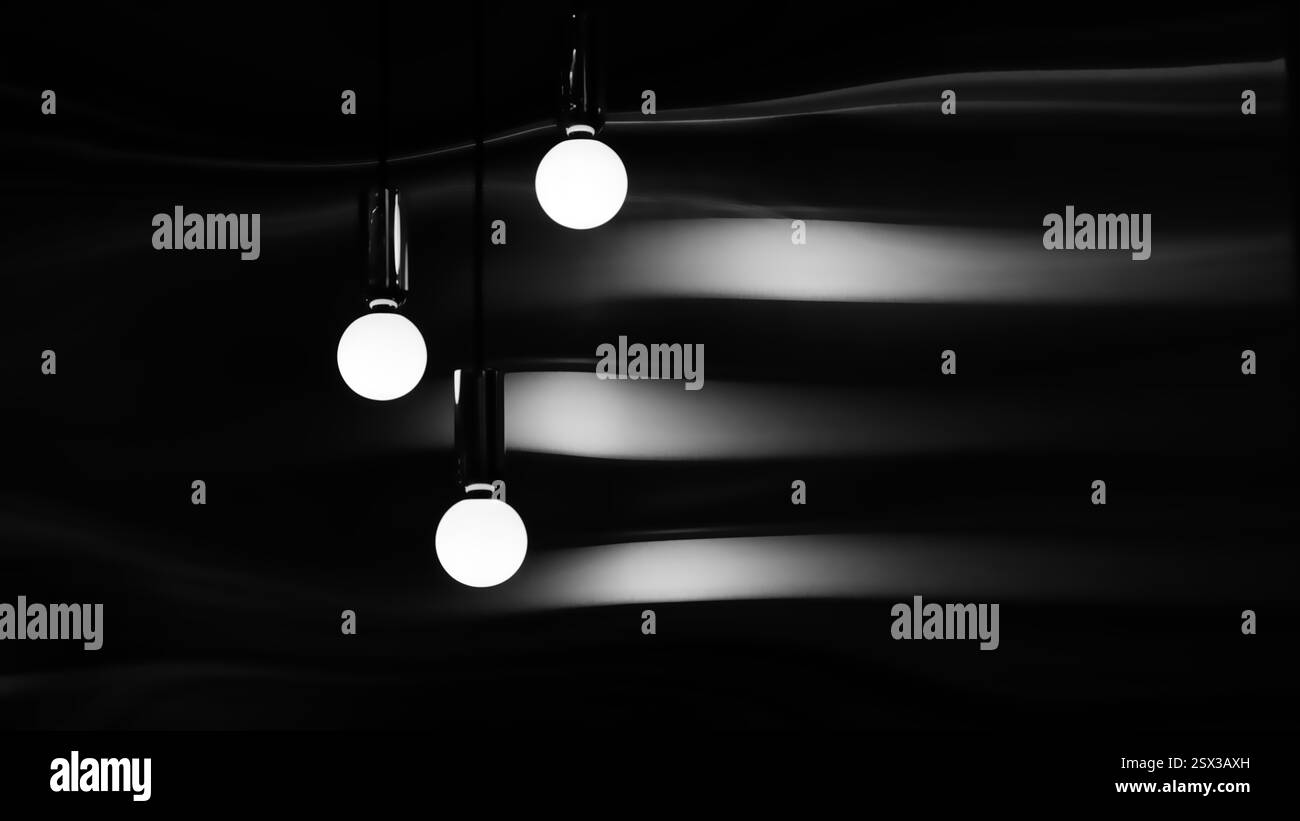 Trois ampoules blanches suspendues au plafond. Les ampoules sont allumées et la pièce est sombre Banque D'Images