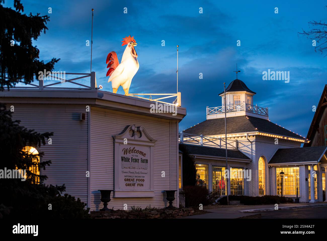 Extérieur du restaurant illuminé décoré d'une statue de coq sur le toit Banque D'Images