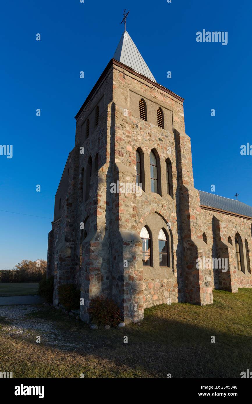 Grand bâtiment en pierre avec un clocher. Le bâtiment est entouré d'herbe. Le ciel est bleu Banque D'Images