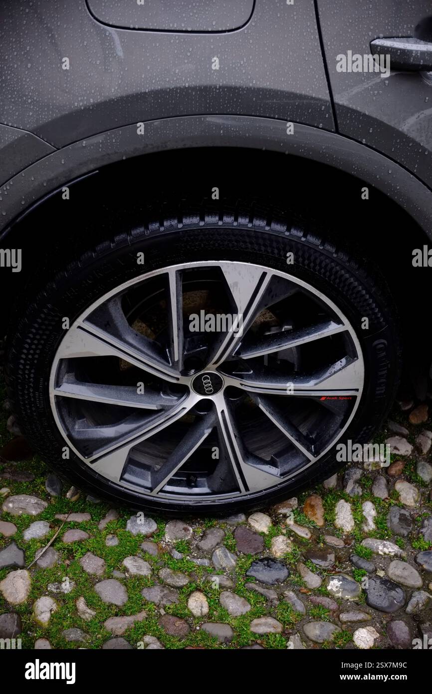 Cremona, Italie 9 février 2025 détail d'une roue Audi garée sur une rue pavée humide, présentant la bande de roulement du pneu et la conception de la jante en alliage Banque D'Images