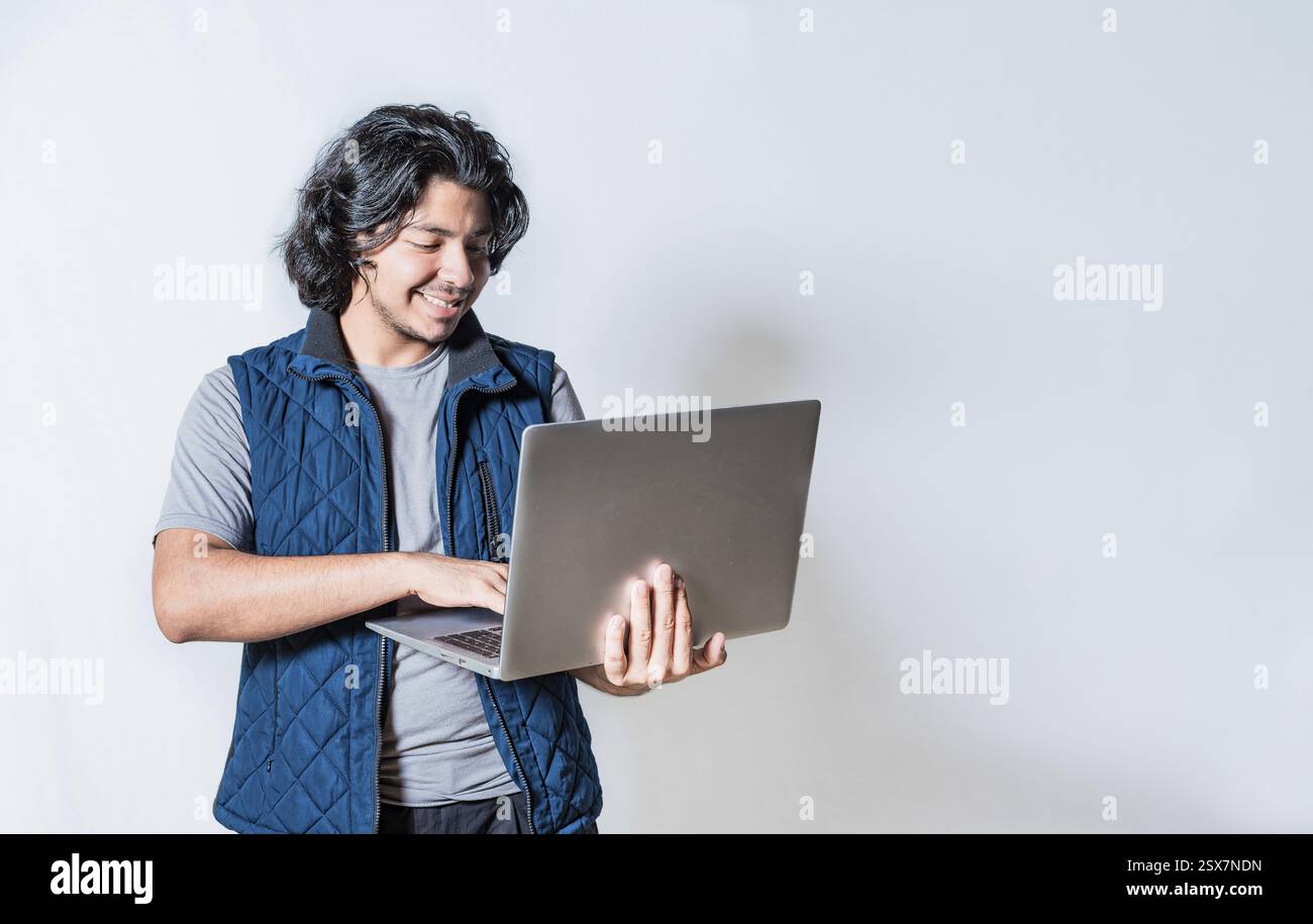 Sourire bel homme regardant une promotion sur ordinateur portable isolé. Heureux jeune homme utilisant un ordinateur portable isolé Banque D'Images