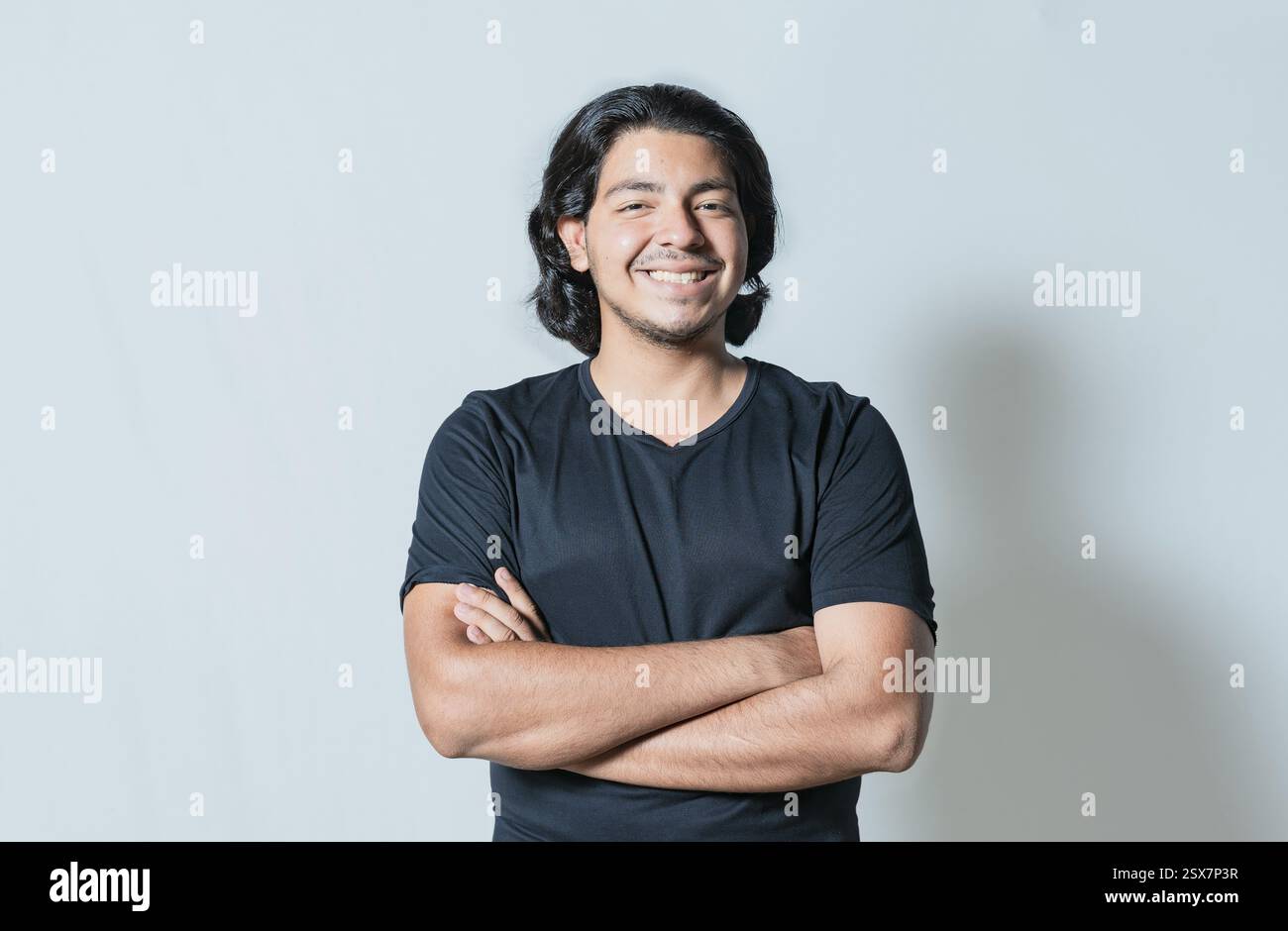 Portrait d'un bel homme latin aux bras croisés isolé. Jeune latin souriant à la caméra Banque D'Images