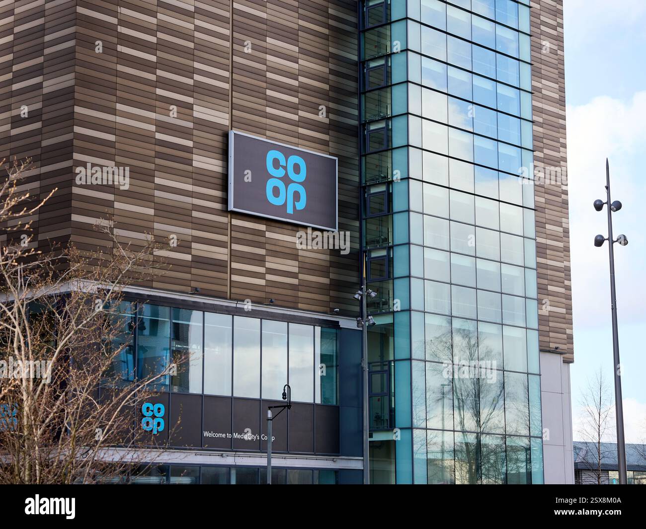 Salford, Manchester, Royaume-Uni, 02-22-2025 : enseigne de magasin COOP. Immeuble de bureaux moderne avec de grandes fenêtres en verre et un design architectural élégant. Banque D'Images