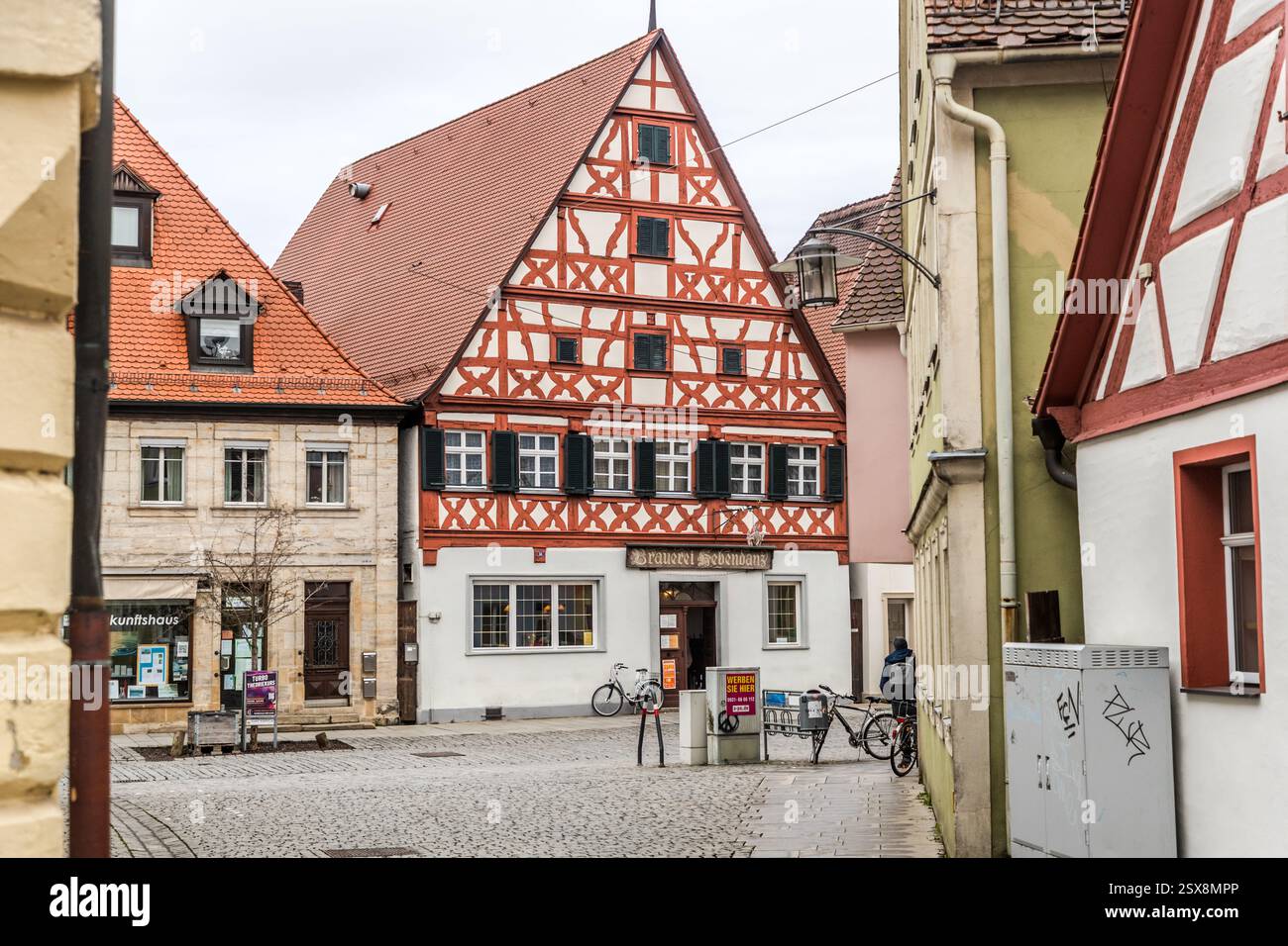 Une rue étroite en Allemagne montre des bâtiments historiques avec des façades à colombages et une personne marchant. Un panneau pour la brasserie Hebendanz est visible sur un bâtiment. Luitpoldstraße, Forchheim, Bavière, Allemagne Banque D'Images