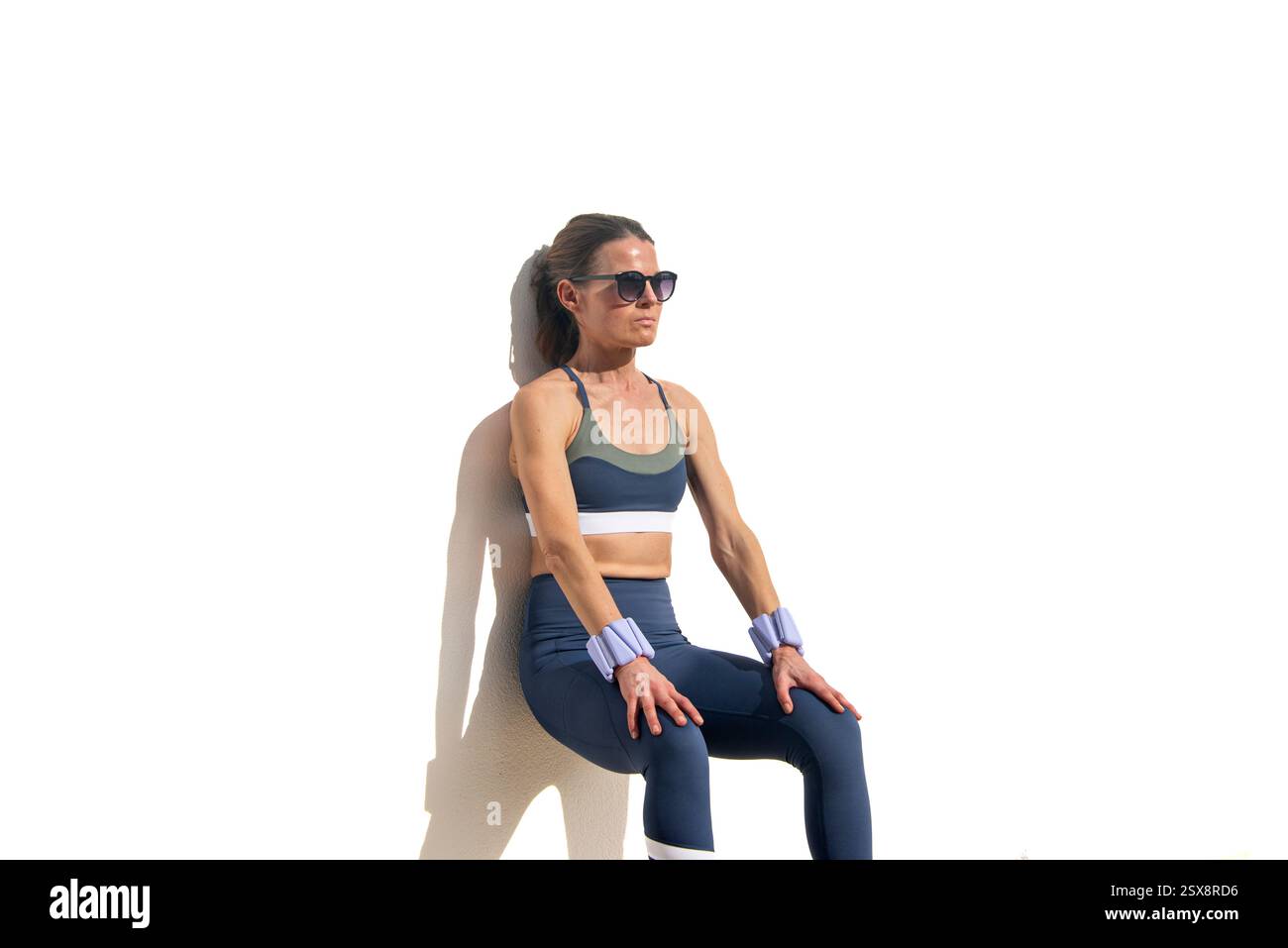 femme sportive portant des poids de poignet réglables faisant un exercice de squat mural Banque D'Images