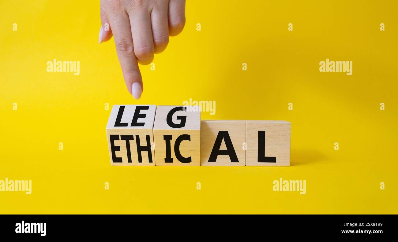 Symbole éthique et juridique. La main d'homme d'affaires pointe sur des cubes en bois tournés avec des mots éthiques et légaux. Beau fond jaune. Affaires et éthique Banque D'Images