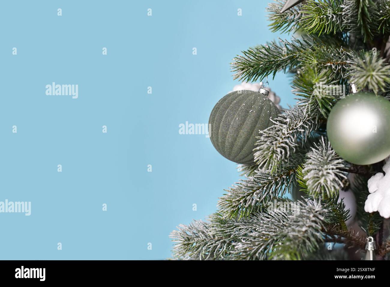 Gros plan de l'arbre de Noël décoré avec des boules d'ornement d'arbre vert de sauge saisonnière sur fond bleu avec espace de copie Banque D'Images