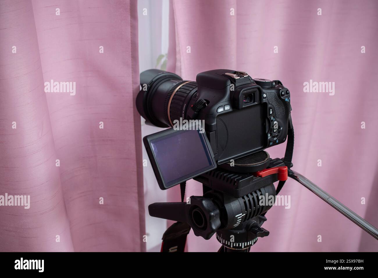 Caméra vidéo numérique cachée derrière des rideaux roses, espionnage des voisins Peeping. Espionnage. Surveillance. Caméra masquée. Paparazzi. Détective privé. Banque D'Images