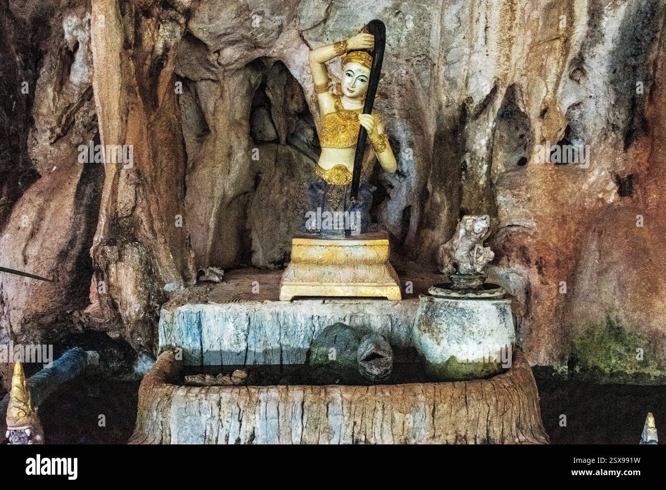 Statue féminine sacrée dans un sanctuaire d'eau à l'intérieur d'une grotte naturelle en Thaïlande, symbolisant la spiritualité, la dévotion et les traditions culturelles anciennes Banque D'Images