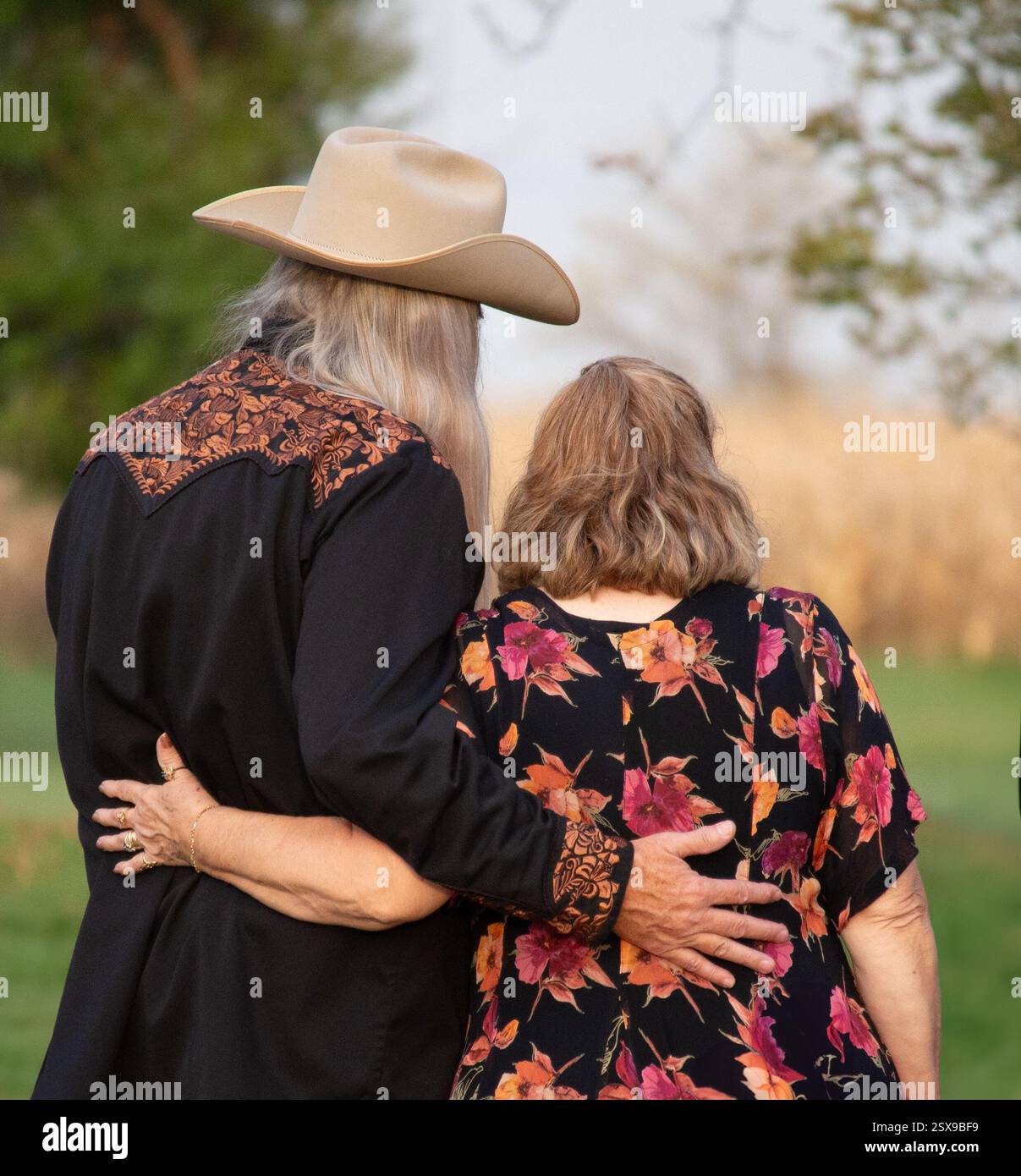 Couple senior embrassant à l'extérieur, portant des vêtements occidentaux, profitant d'un après-midi d'automne paisible ensemble. Banque D'Images