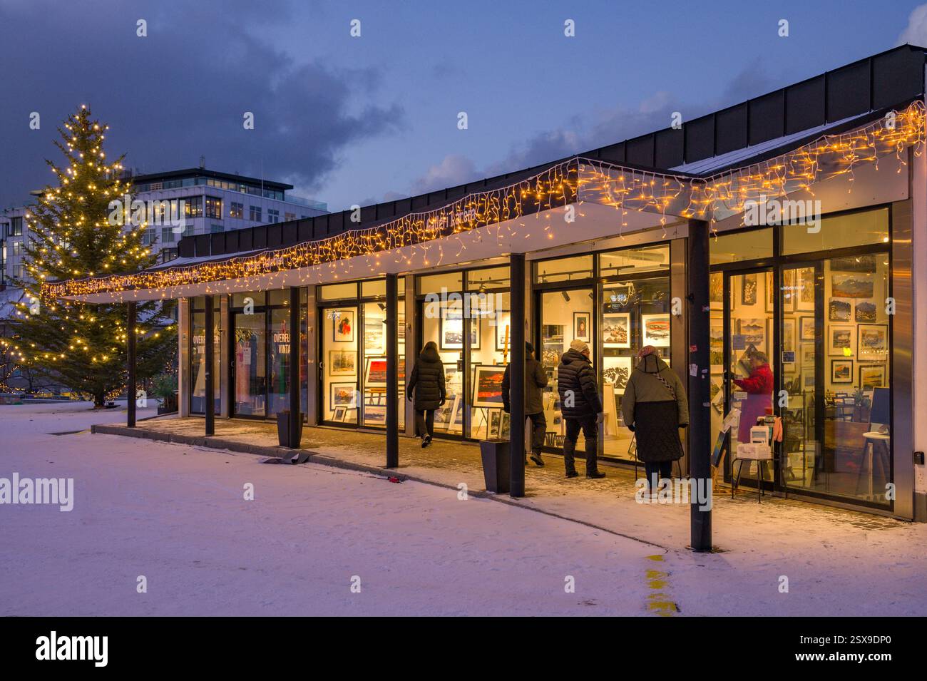 Une petite galerie d'art dans le centre-ville de Bodø avec des gens regardant des œuvres d'art sous la nuit polaire en automne, Norvège Banque D'Images