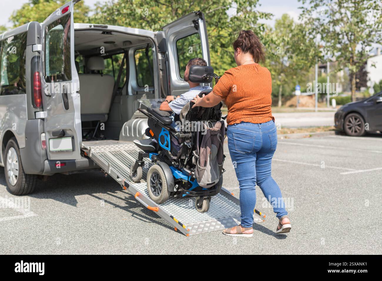 Femme assistante pour personnes handicapées ajustant l'équipement pour fauteuils roulants dans un véhicule accessible. Concept de service d'aide à la mobilité. Banque D'Images