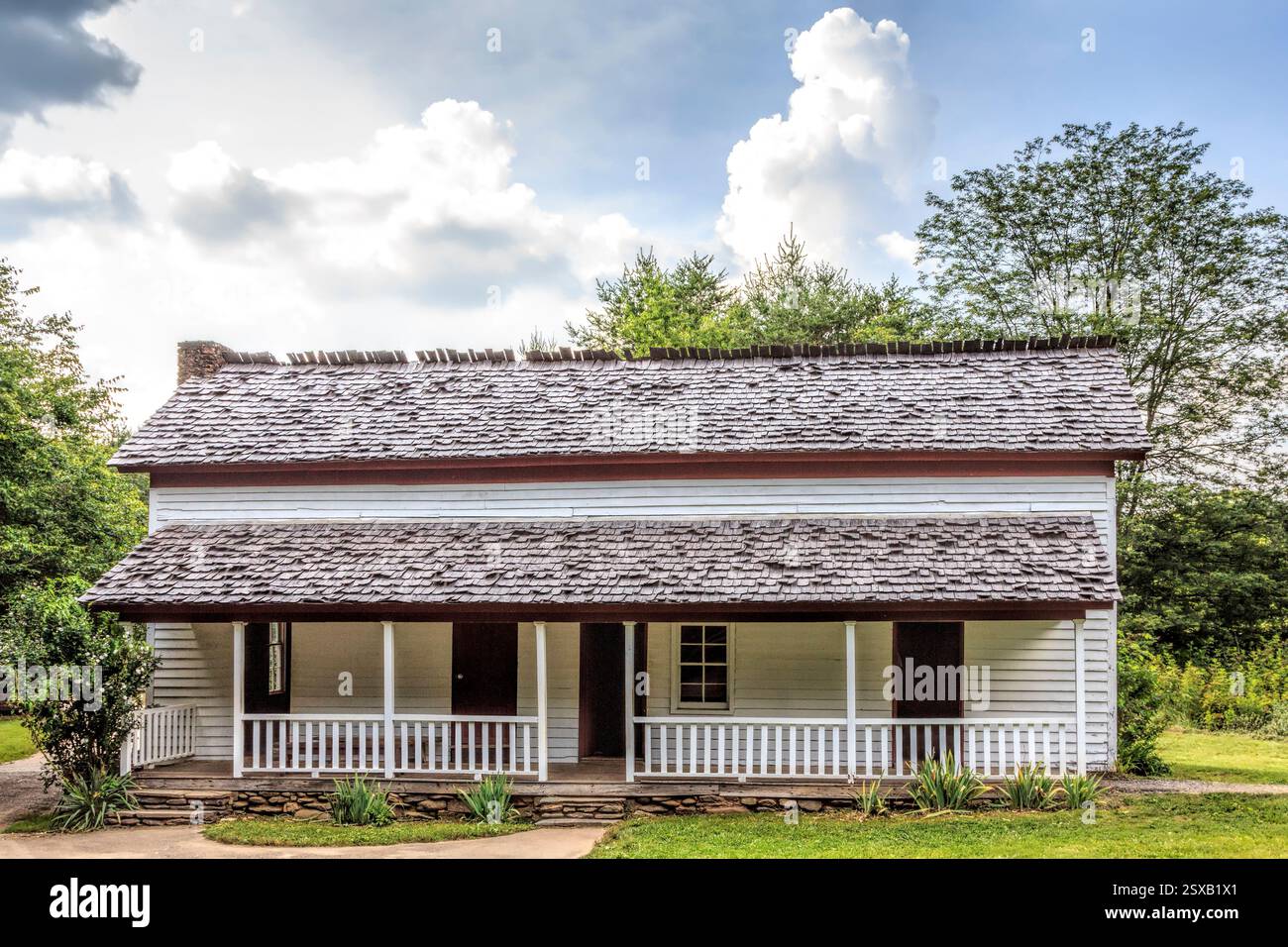 Maison blanche avec un toit en bardeaux. Le toit est incliné. La maison a un porche Banque D'Images