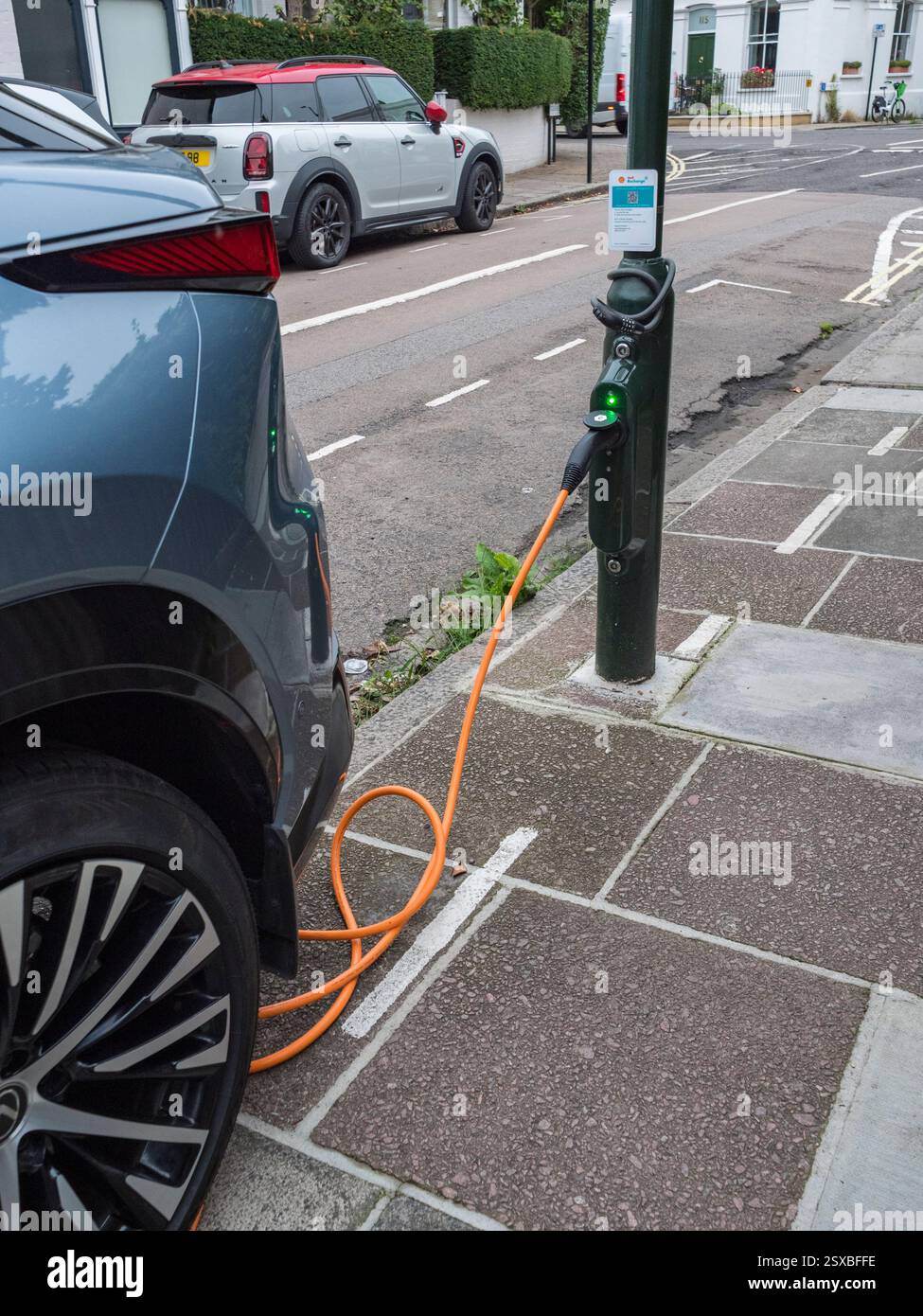 Une voiture électrique se recharge à partir d'une borne de recharge Shell dans un lampadaire de bord de route à Barnes, Londres, Royaume-Uni. Banque D'Images