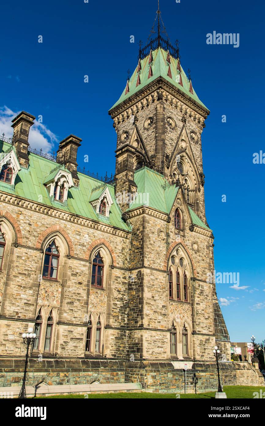 Grand bâtiment avec tour de l'horloge. Le bâtiment est en pierre et a un toit vert Banque D'Images