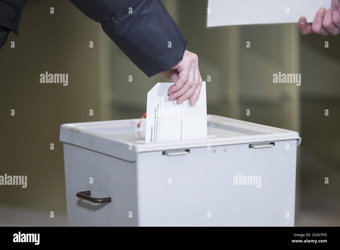 Une personne jette son bulletin de vote dans l'urne lorsqu'elle vote pour l'élection au 21e Bundestag au stati de scrutin IHK Potsdam Banque D'Images