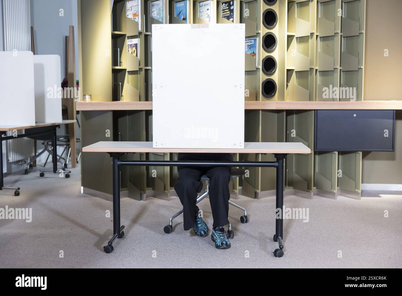 Une personne est assise dans un bureau de vote pendant le vote pour l'élection au 21e Bundestag au bureau de vote IHK Potsdam le 23 février 2025 Banque D'Images