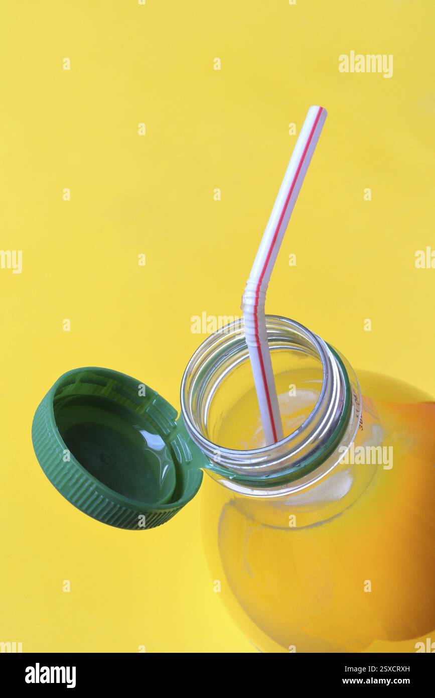 Jus d'orange dans une bouteille en plastique avec bouchon et paille Banque D'Images