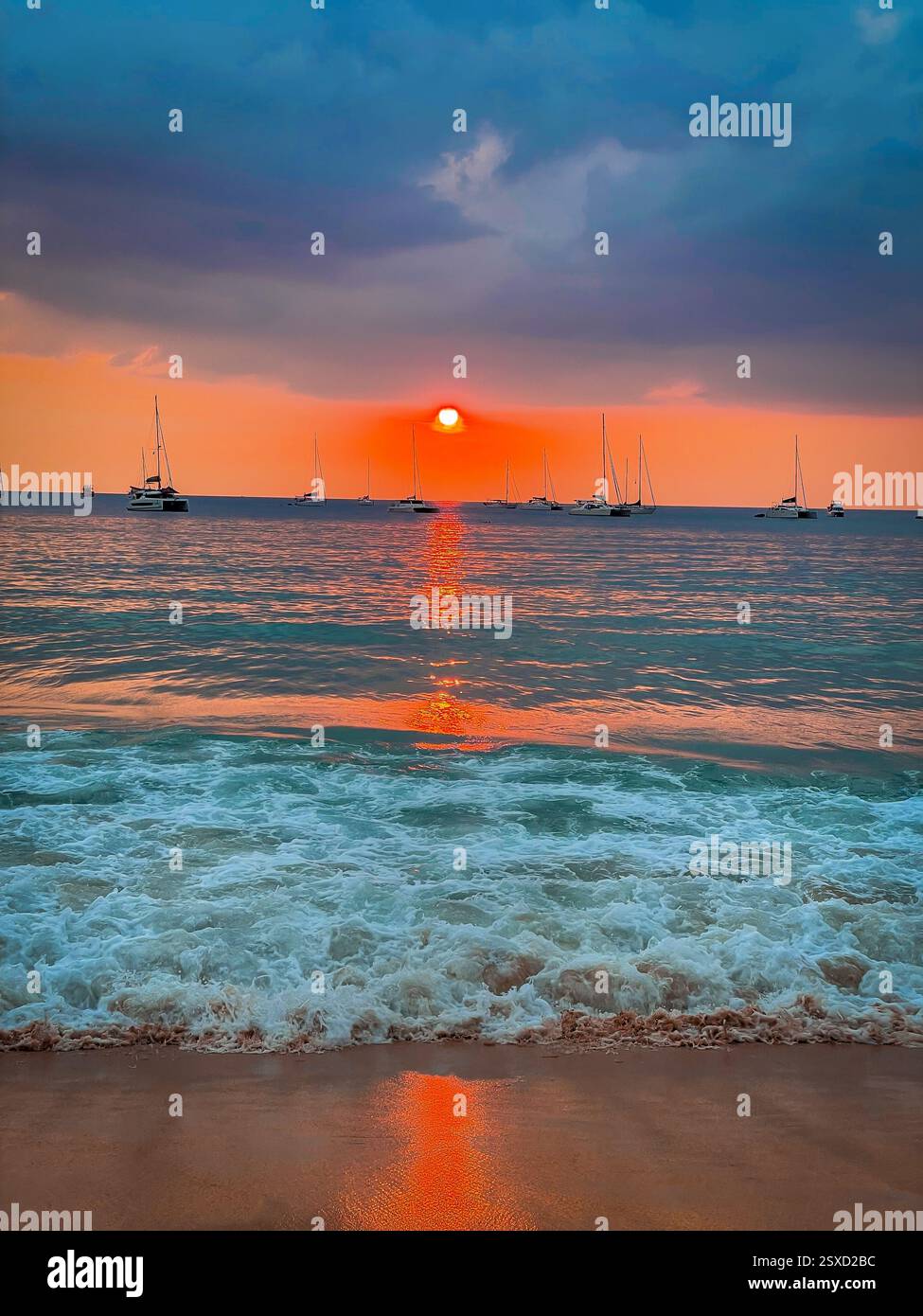 Rayon de soleil brillant sur la mer calme, bateaux et vagues au coucher du soleil le soleil orange vif se couche lentement à l'horizon, projetant un faisceau magique de lumière qui danse Banque D'Images