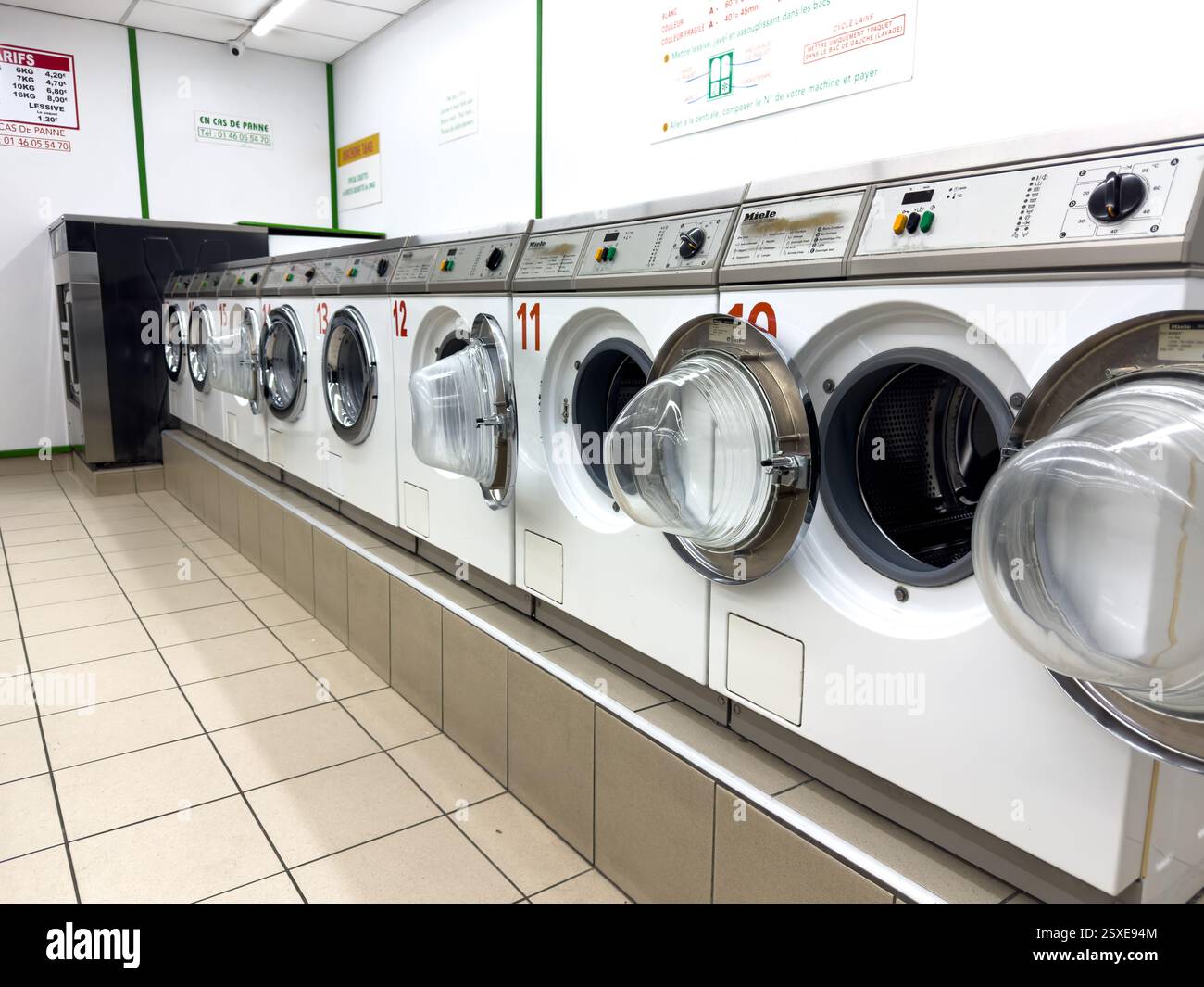 Buanderie lumineuse remplie de machines en attente de service par une journée ensoleillée Banque D'Images