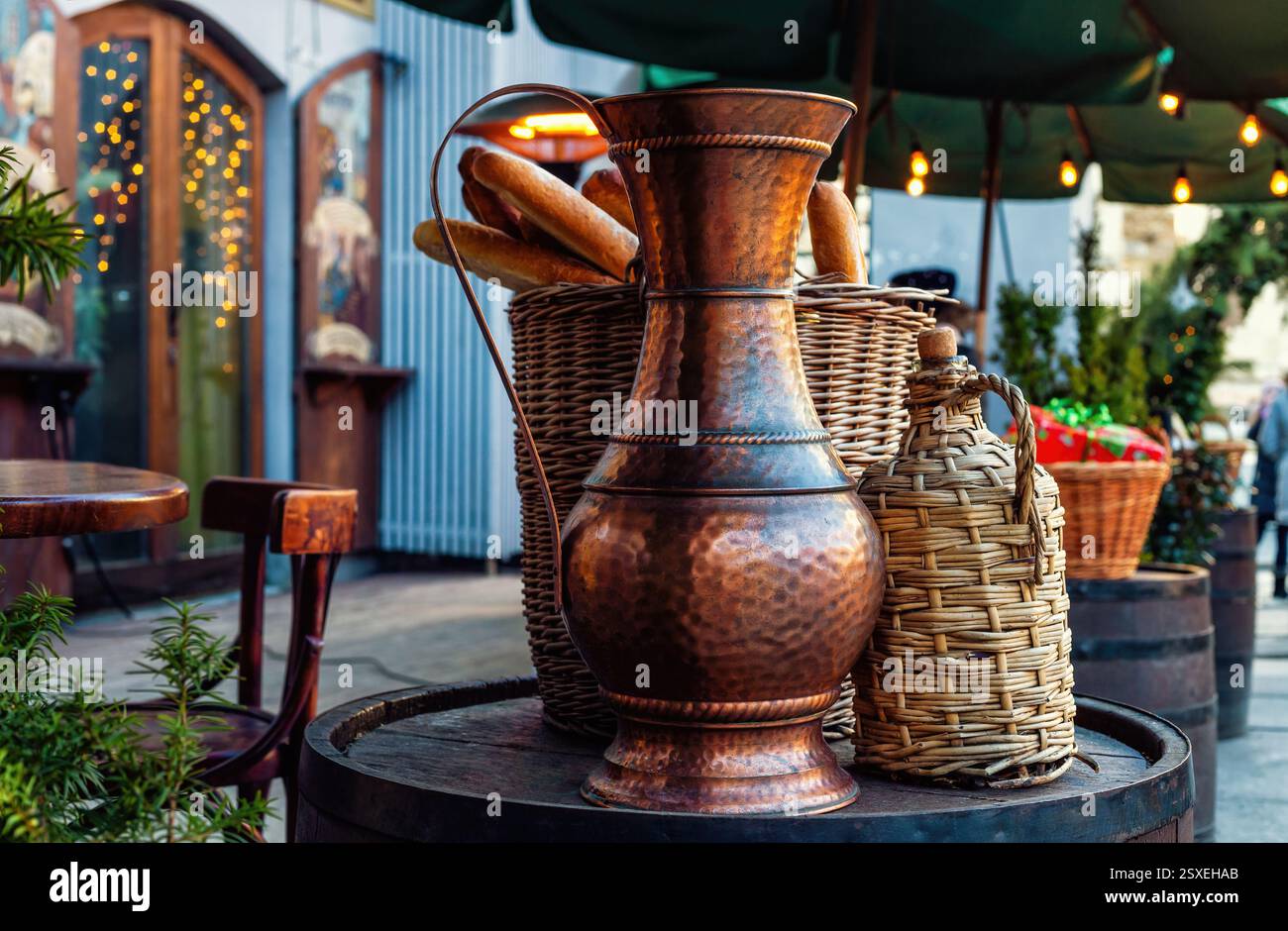 Pot en cuivre vintage bouteille de vin tressée et baguette française dans un panier en osier debout sur un tonneau en bois Banque D'Images