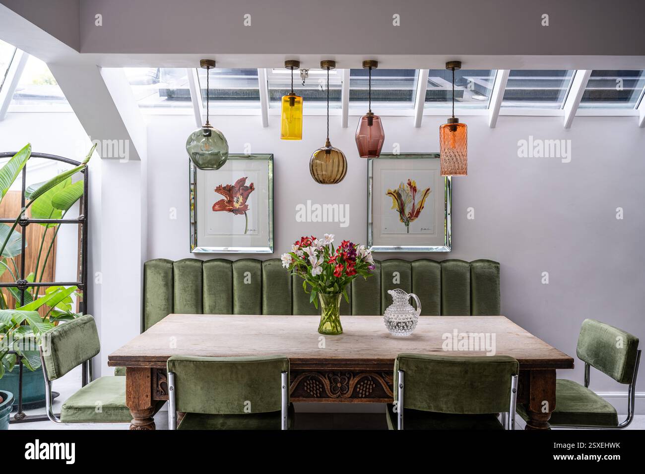 Cinq abat-jour en verre soufflé à la main avec chaises chromées rétro et banc rembourré de vert sauge. Maison West London. Londres, Royaume-Uni. Banque D'Images