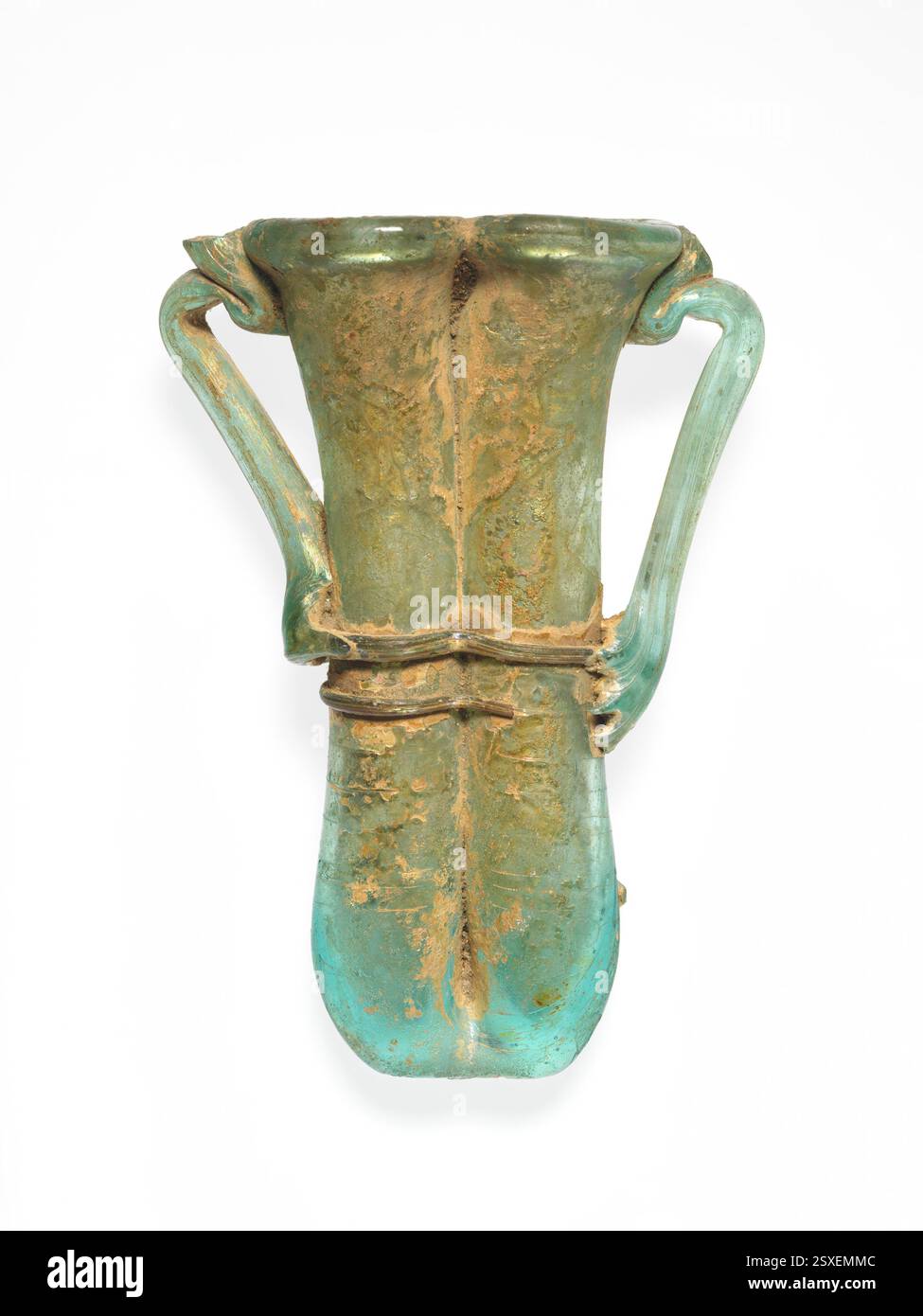 Flacon cosmétique double en verre (tube de kohl), romain, IVe–Ve siècle ce, verre bleu-vert translucide. Comprend des poignées et des traînées de la même couleur, un rebord tubulaire renversé et un corps composé de deux tubes fabriqués à partir d'une seule rassemblement gonflé. Décoré avec des sentiers en spirale et fins. L'extérieur présente des altérations, des piqûres et des intempéries irisées, tandis que l'intérieur présente des altérations crémeuses et des incrustations du sol. Banque D'Images