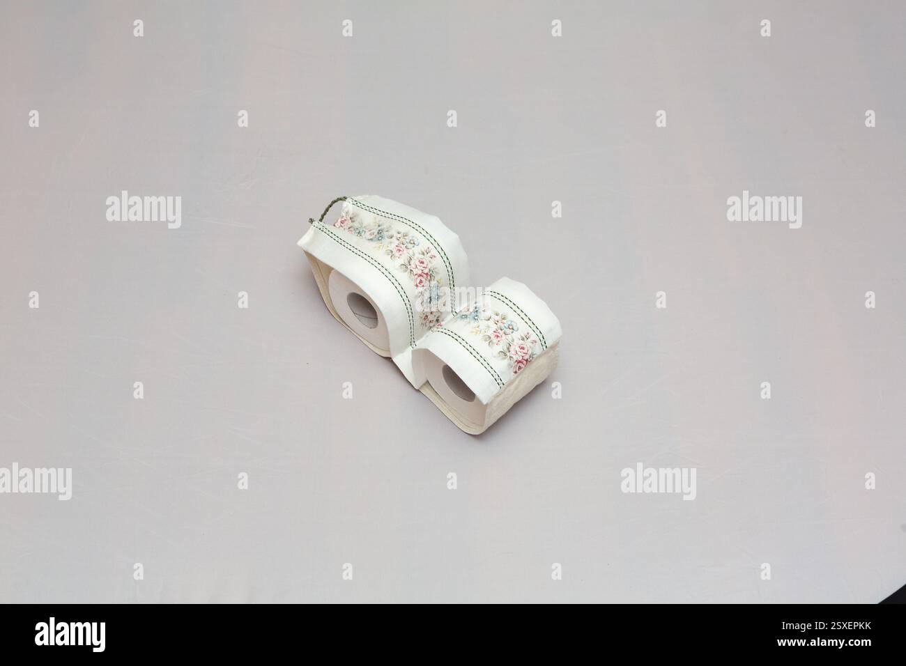 Deux rouleaux de papier toilette recouverts de tissu floral reposent sur une table, ajoutant une touche d'élégance à un indispensable de la salle de bain Banque D'Images