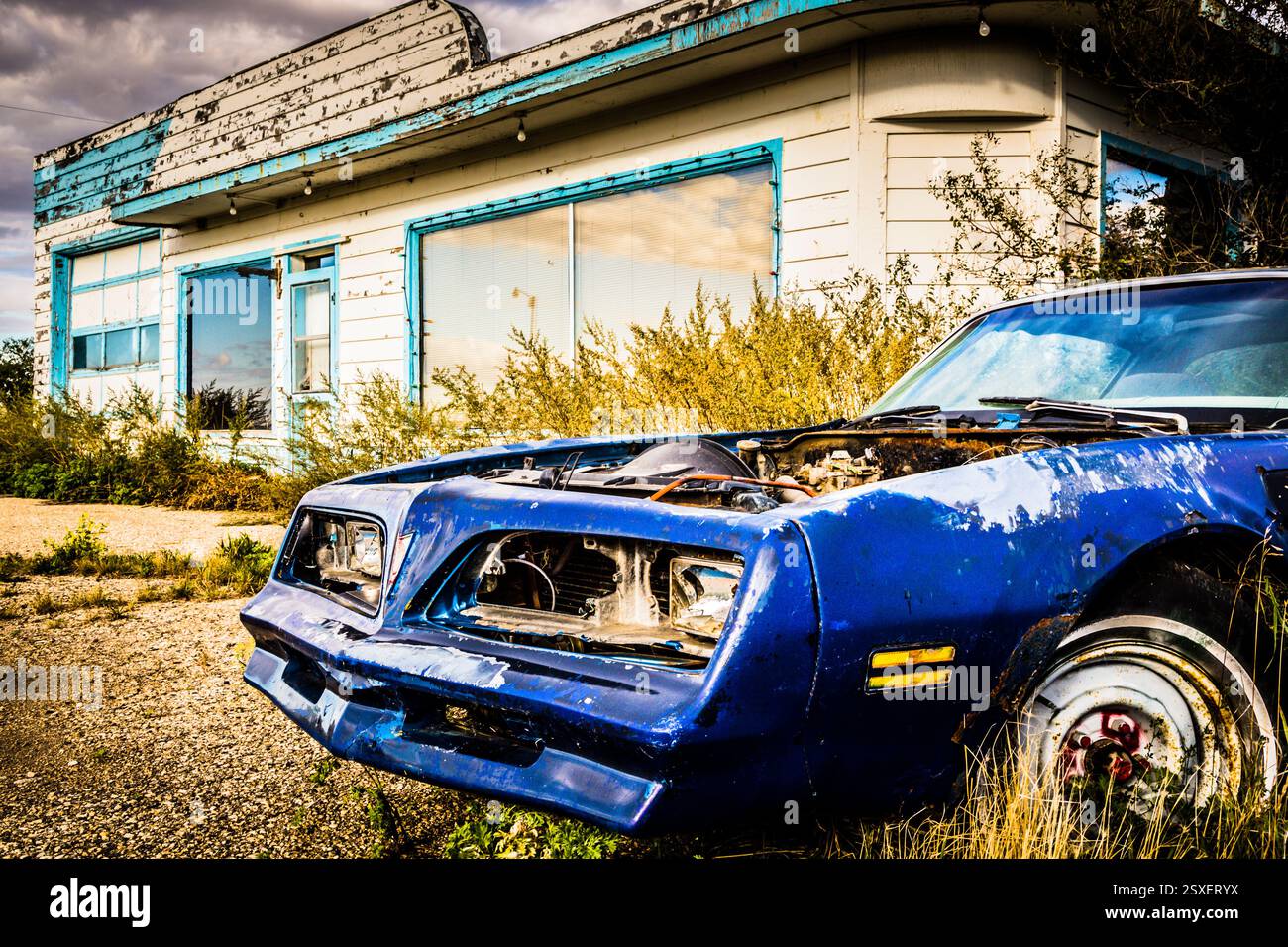 Blue car est garé devant un bâtiment blanc. La voiture est vieille et a un phare cassé Banque D'Images