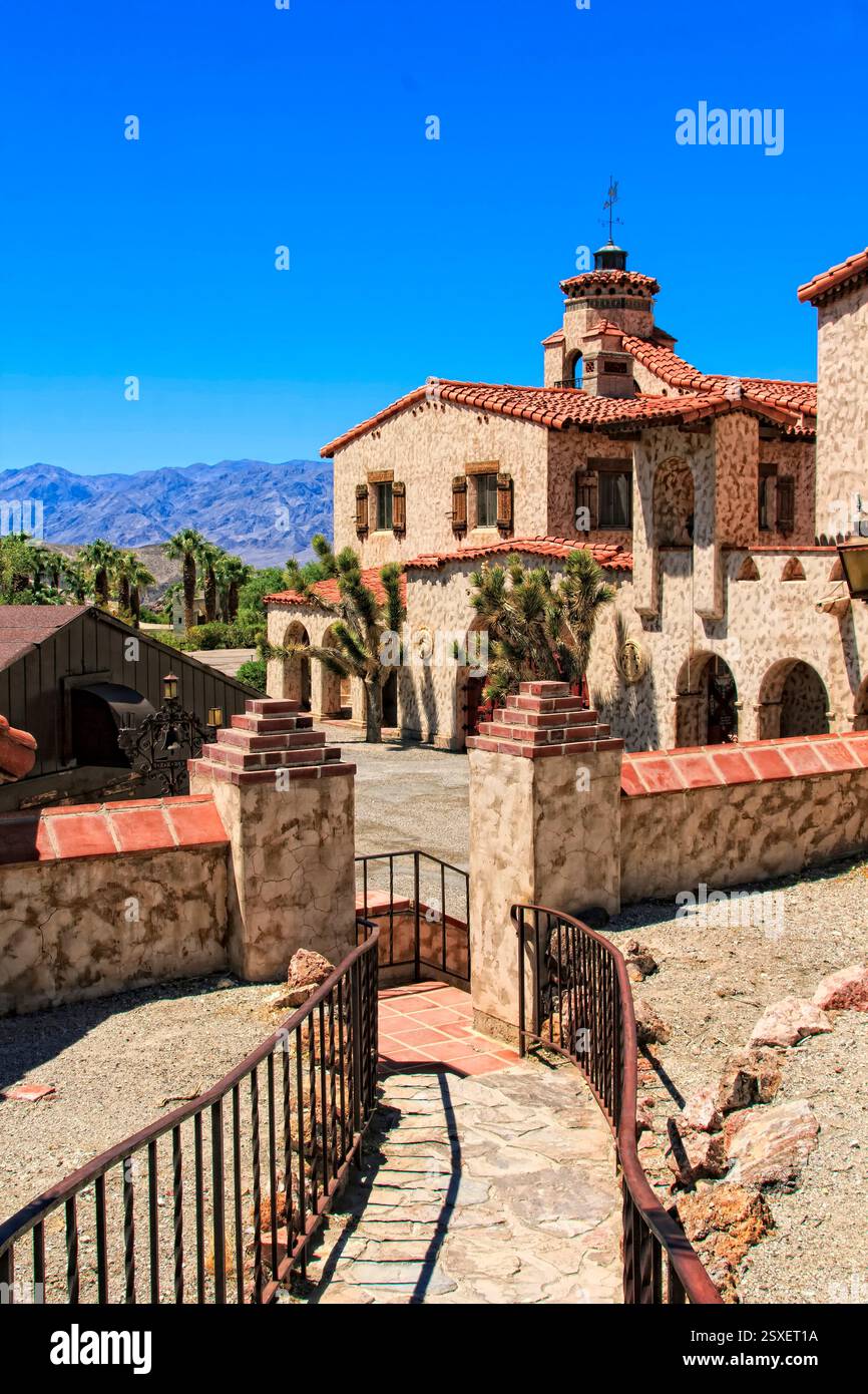 Maison avec un toit rouge et une clôture blanche. La maison est entourée d'un mur de pierre Banque D'Images