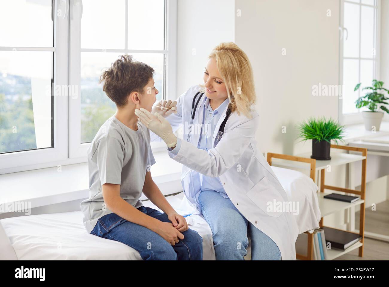 La pédiatre féminine à la clinique regarde la gorge des garçons, en gros plan Banque D'Images
