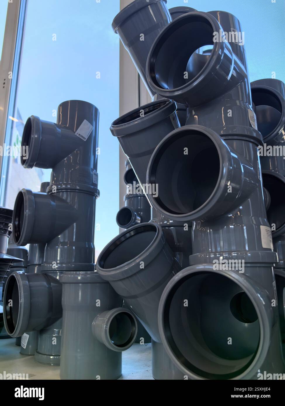 Une variété de tuyaux gris sont disposés dans une formation unique, presque semblable à une sculpture. Leurs formes soulignent à la fois le design fonctionnel et l'attrait esthétique, Banque D'Images
