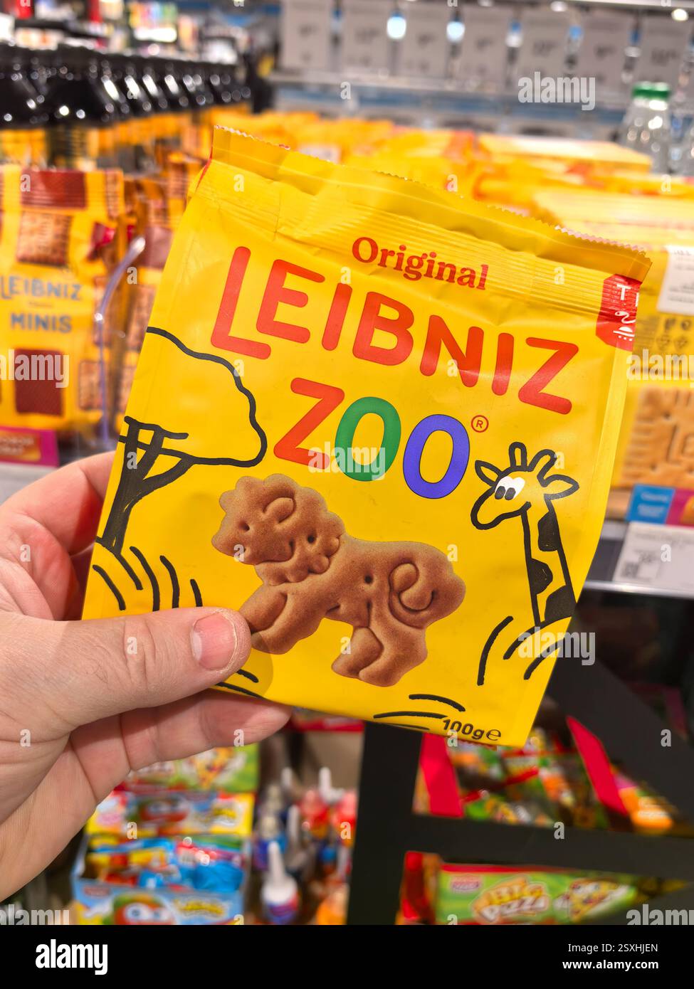 Bobruisk, Biélorussie - 16 février 2025 : une main tient un paquet jaune vif de biscuits en forme d'animal tout en étant entouré de divers autres snacks dans un vibran Banque D'Images