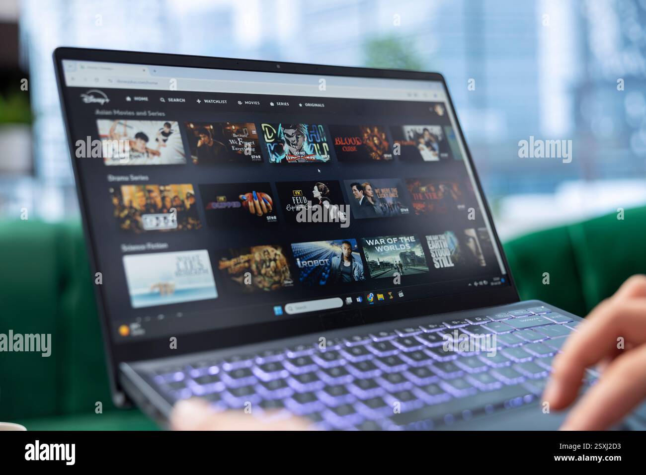 Bucarest, Roumanie - 30 juillet 2024 - PDG à la recherche d'un film sur Disney plus en ligne, défilement à travers la sélection de plate-forme de streaming de films sur la page Web Google. Administrateur commercial détendu. Banque D'Images