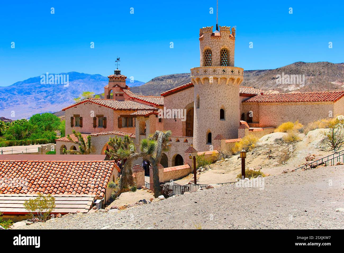 Grand bâtiment avec un toit rouge et une tour. Le bâtiment est entouré d'un chemin de terre Banque D'Images