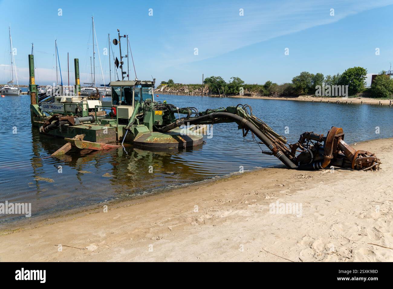 Engure, Lettonie - 2 juin 2024 : des travaux de dragage sont en cours dans la zone portuaire, avec le rivage au premier plan équipement d'un navire pour les travaux sur un Banque D'Images