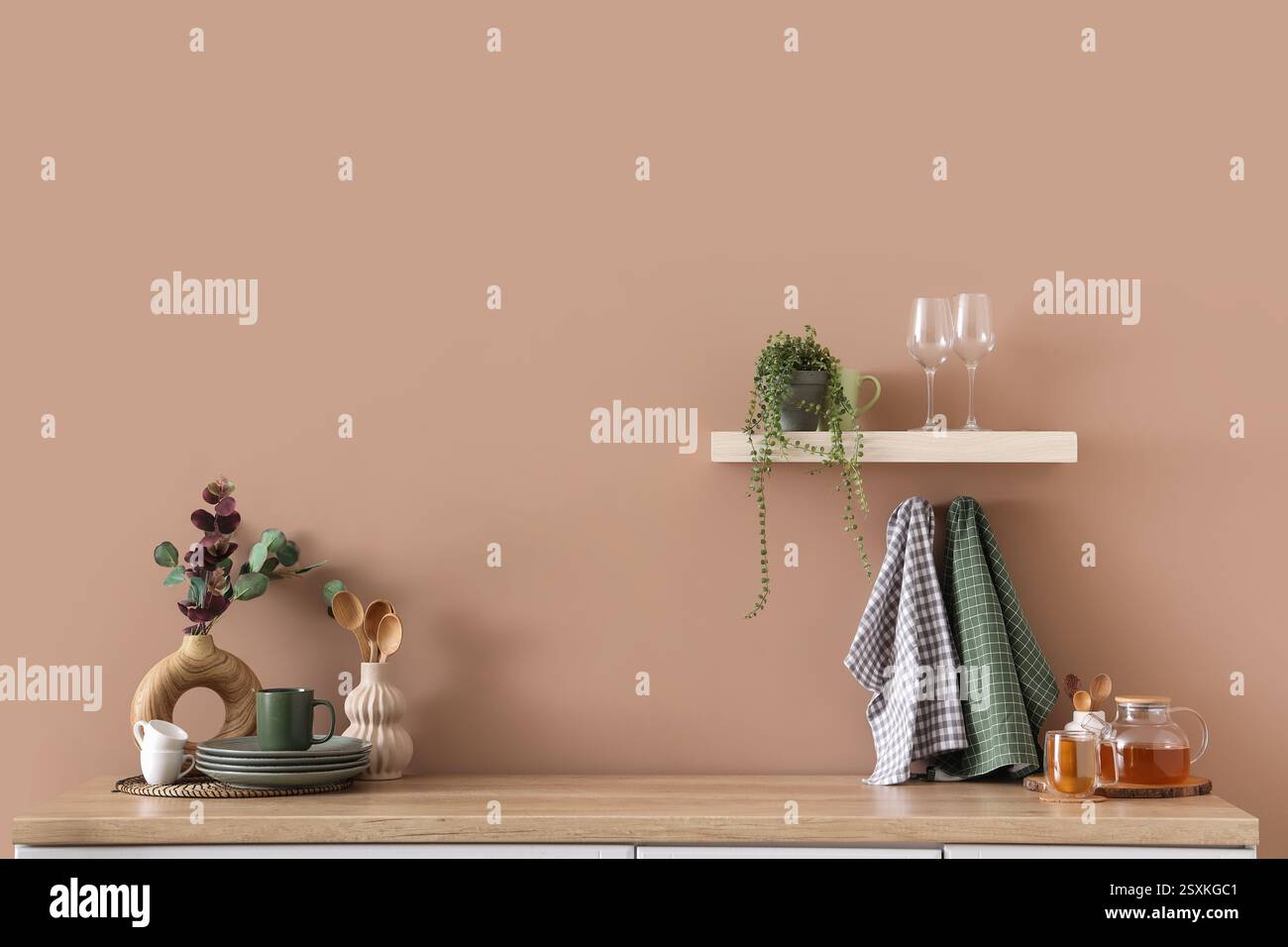 Comptoir avec vaisselle, thé et serviettes sur mur beige dans la cuisine Banque D'Images