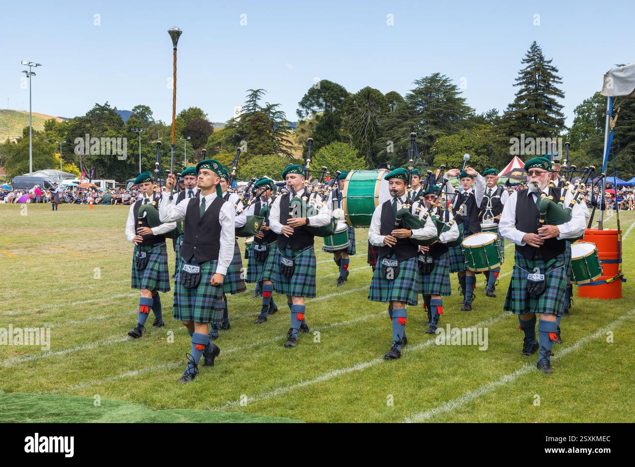 Un orchestre Highland en costumes écossais traditionnels. Un major de tambour mène, tenant sa masse en l'air Banque D'Images