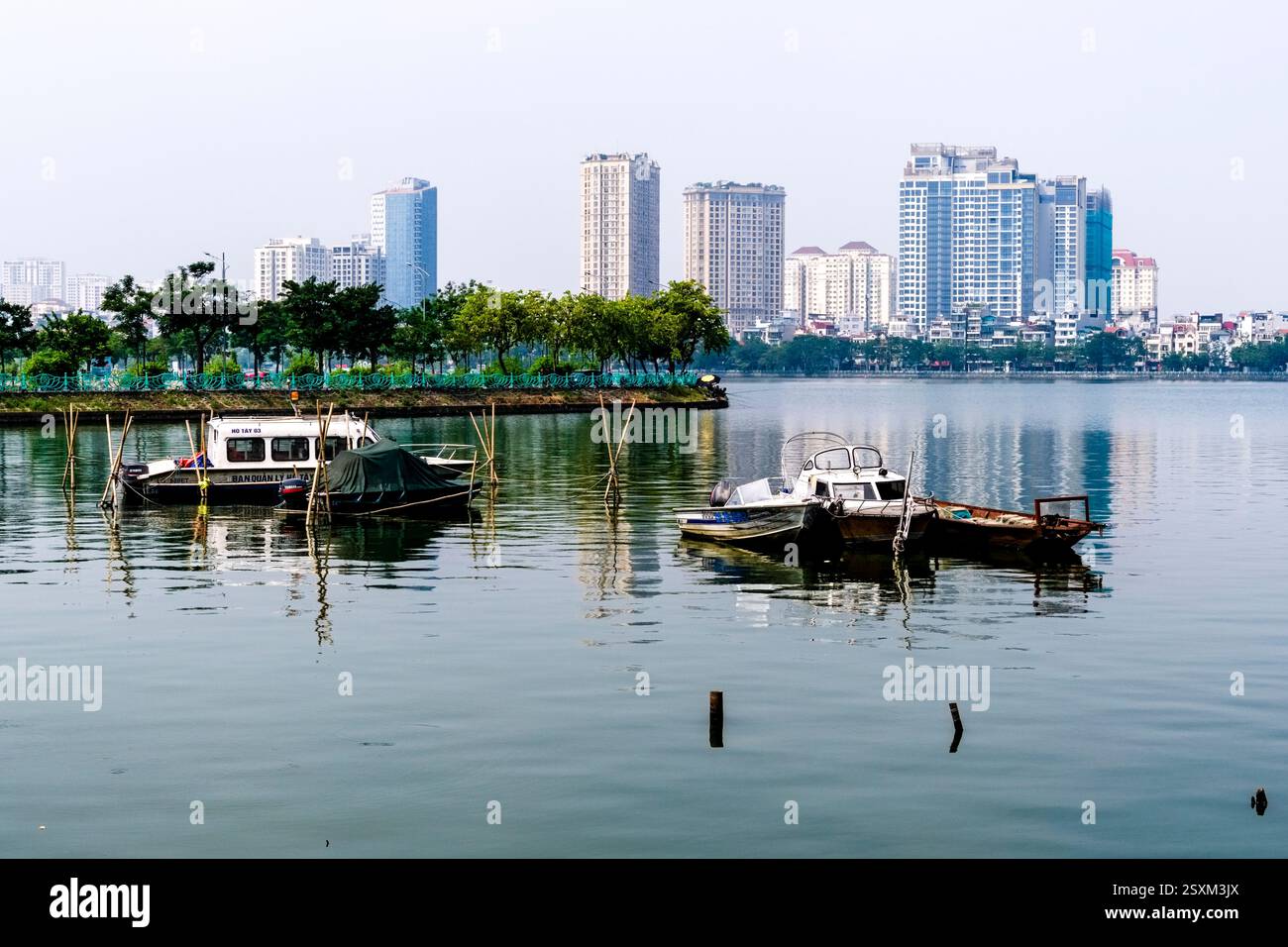 L'horizon du centre-ville de Hanoi se reflète sur la surface du lac de l'Ouest, Ho Tay, bateaux de pêche à l'ancre. Banque D'Images