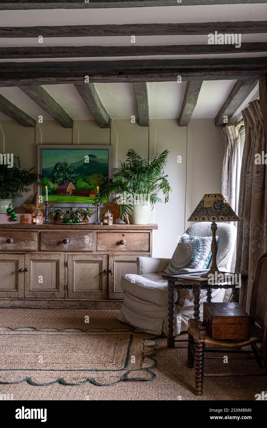 Oeuvre d'art par Victoria Threlfall au-dessus de commode en bois avec tapis de jute dans la ferme rénovée East Sussex Tudor datant de 1540, Angleterre, Royaume-Uni. Banque D'Images